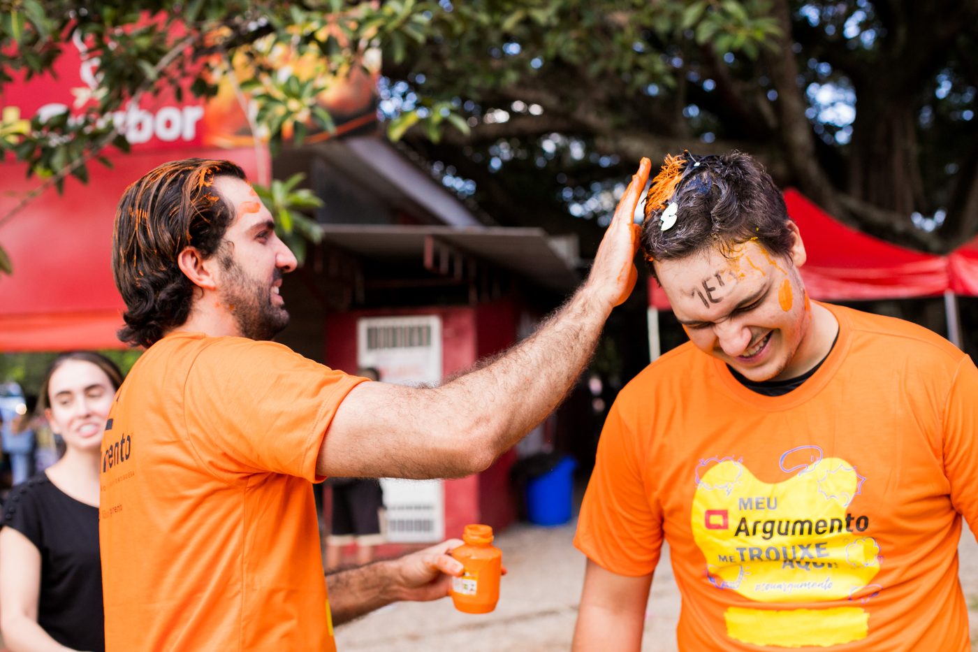 Professor pinta de laranja o cabelo de um aluno aprovado