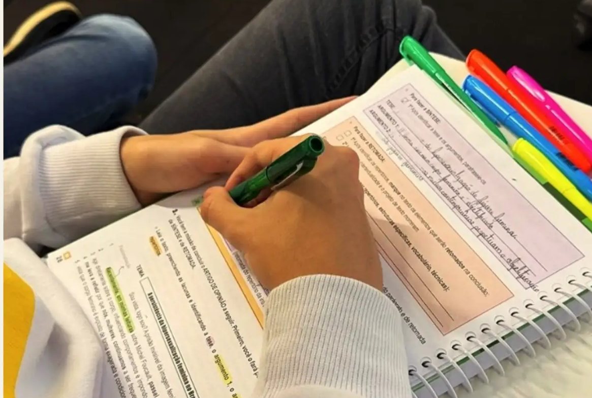 Estudante marcando o texto do livro com canetas coloridas